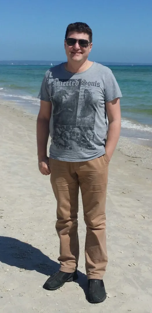 Man standing on sunny beach, smiling.